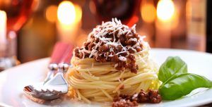 spaghetti on a plate served with red wine