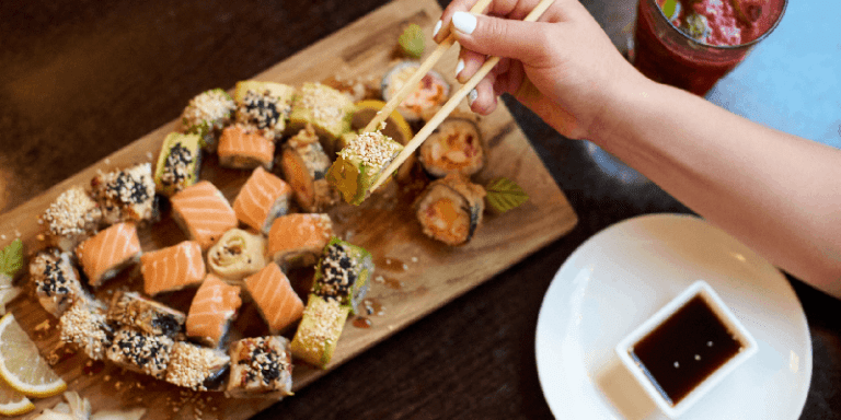 a tray of sushi rolls and raw sashimi with soy sauce