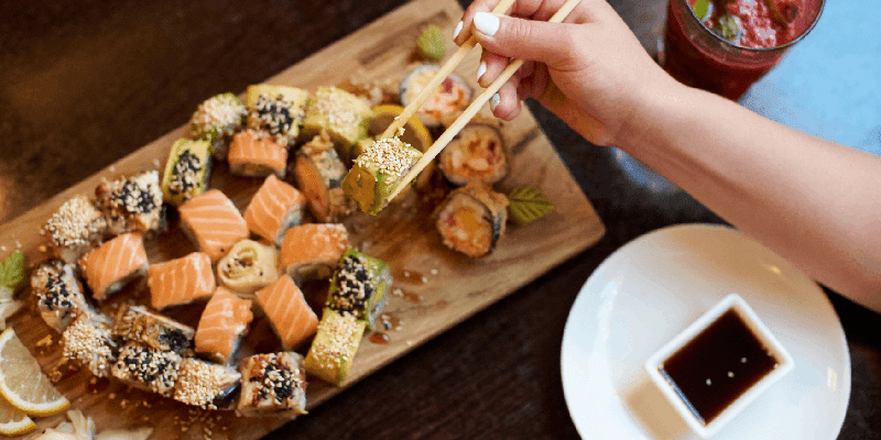 a tray of sushi rolls and raw sashimi with soy sauce