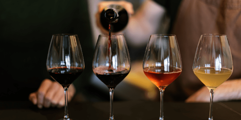 a wine professional pouring wine into several glasses for a tasting