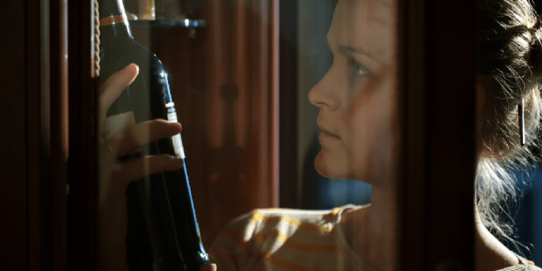 a woman inspecting a bottle of wine trying to determine if the wine is bad or good