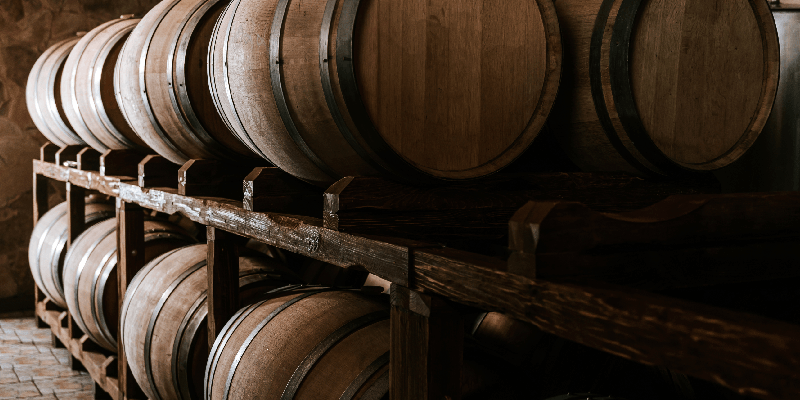 barrels of oak with wine inside laying horizontally 