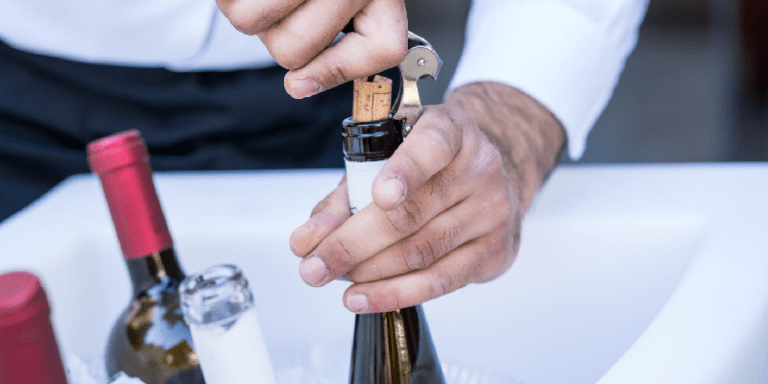a sommelier opening a bottle of wine using a corkscrew