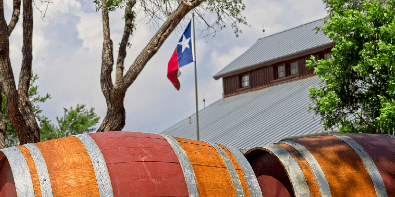 a barrel of wine next to the texas flag