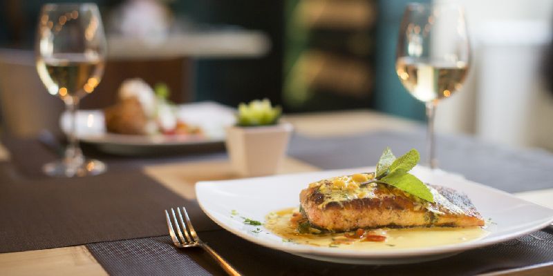 grilled salmon on a plate with a glass of white wine, one of the best wine pairings with salmon