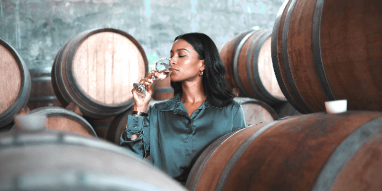 a woman drinking a glass of Chardonnay wine that has been aged in barrels