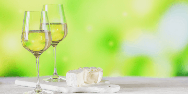 two glasses of white wine next to fresh brie cheese