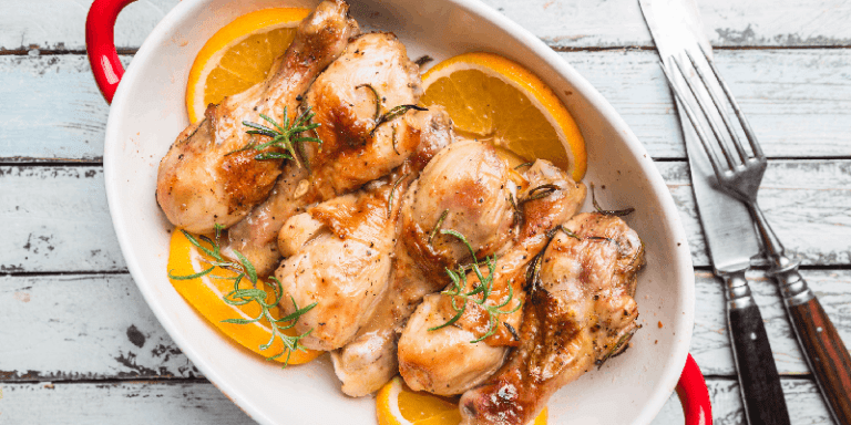 a dish of cooked chicken with oranges and seasonings