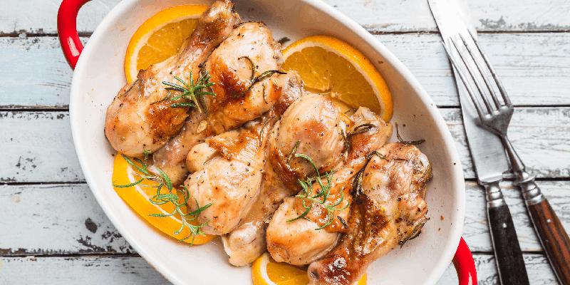 a dish of cooked chicken with oranges and seasonings