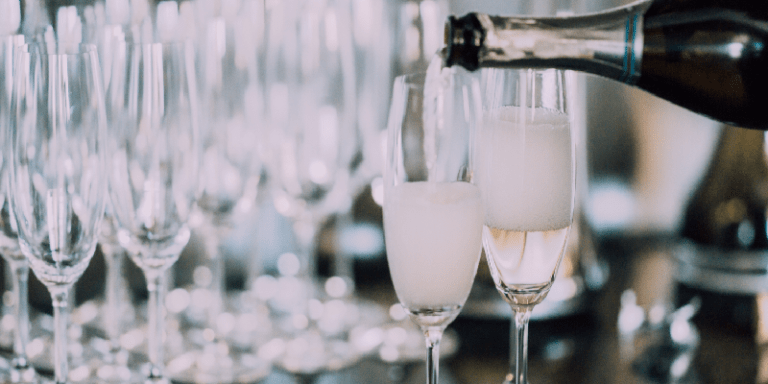 a bottle of Champagne being poured into flute glasses