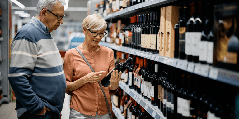 a couple reading a wine bottle label in the supermarket
